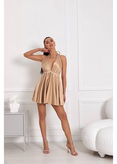 a woman is posing in a tan dress