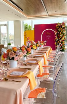 a long table set up with place settings and flowers in vases on the tables