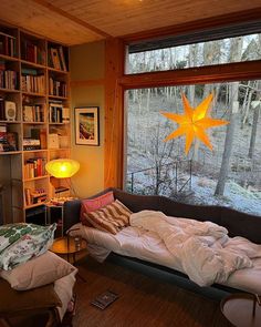 a bedroom with a large window that looks out onto the woods and has a bed in front of it