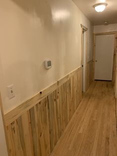 an empty hallway with wood paneling and white walls in a house that is being renovated