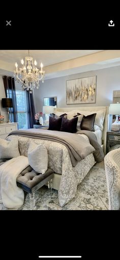 a large bed sitting in the middle of a bedroom next to a chandelier