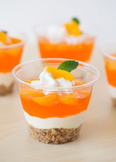 small desserts with orange and white toppings in plastic cups on a wooden table