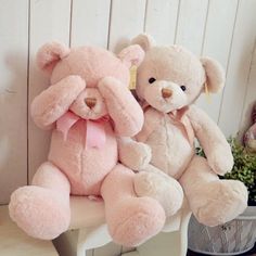 two pink teddy bears sitting on a white chair