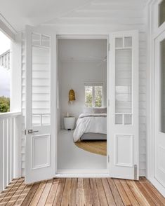 an open door leading to a bedroom with white walls and wood flooring on the outside