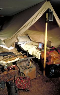 there is a tent that has two beds and luggage under it with a laptop on the bed