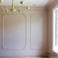 a chandelier hangs from the ceiling in an empty room with white paneling