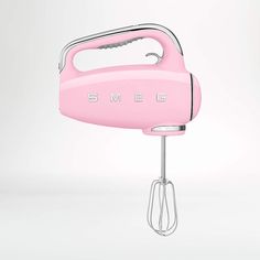 an electric hand mixer with the word smeg on it's side, in pink