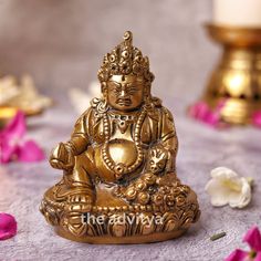 a golden buddha statue sitting on top of a table next to some white and pink flowers