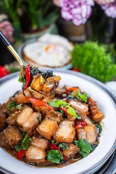 a plate full of food with chopsticks sticking out of the meat and vegetables