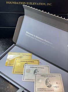 three american express credit cards sitting in a metal case on top of a black counter