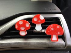 three red and white mushrooms sitting on the dashboard of a car