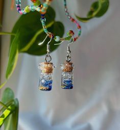 These handmade resin potion bottle earrings are a magical blend of fantasy and sparkle. Each miniature bottle is filled with enchanting glitter and designed to look like it's overflowing with playful bubbles, capturing the essence of a mystical elixir. The glossy resin finish adds depth and shimmer, making the earrings glisten with every movement. Lightweight and full of charm, these potion bottle earrings are perfect for anyone who loves a touch of magic and whimsy in their accessories. *these Glass Bottle Earrings, Whimsical Resin Jewelry For Party, Potion Earrings, Potion Necklace, Bottle Earrings, Miniature Bottles, Earrings Resin, Potion Bottle, Halloween Projects