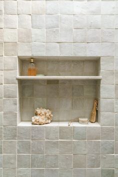 a white tiled wall with shelves and items on it