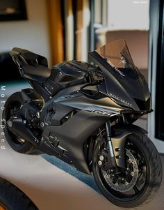 a black motorcycle parked on top of a white floor next to a tv monitor screen