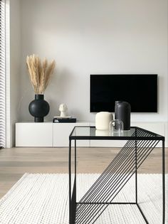 a black and white living room with a television on the wall, vases in front of it