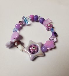 Inspired by decora, clown, and kidcore fashion, this all purple bracelet has a variety of beads including mushrooms, hearts, stars, and more. It is on a two strand stretch cord to accommodate various wrists. Mine is a smallish adult wrist for reference. Purple Monochromatic, Kidcore Fashion, Resin Bracelet, Purple Bracelet, Jewelry Inspo, Violet, Jewelry Bracelets, Bracelet, Handmade Items