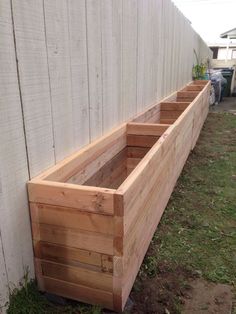 three wooden planters sitting next to a white fence