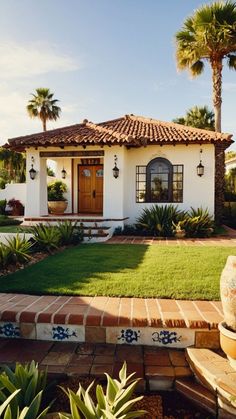 a white house with palm trees in the front yard and grass on the side walk