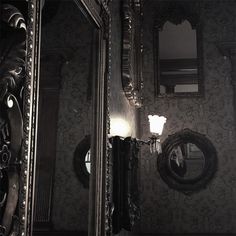 an ornately decorated wall mirror in front of a dark room with black and white wallpaper