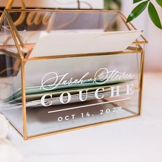 a clear acrylic box with some writing on it and a plant in the background