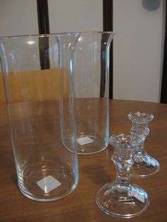 two clear glass vases sitting on top of a wooden table next to each other