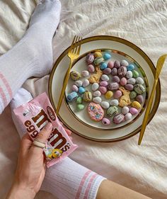 a person holding a candy bar in front of a plate with cereal and cookies on it