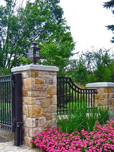 an iron gate with flowers in the foreground