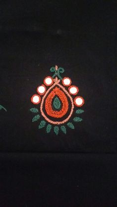 an embroidered cloth with candles on it in front of a black background and green leaves