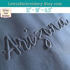 an embroidered name is shown on the back of a blue jean's jacket with white stitching