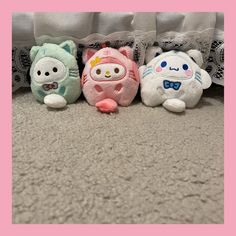 three small stuffed animals sitting next to each other on the floor in front of a curtain