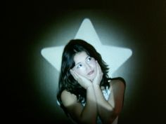 a woman with her hand on her face in front of a star shaped light fixture