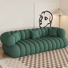 a green couch sitting on top of a checkered floor next to a white wall