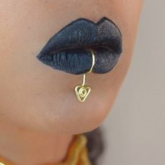 a close up shot of a woman's face with black lipstick and gold jewelry