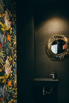 a bathroom with wallpaper and a mirror on the wall next to a black sink