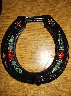 a close up of a metal object on a wooden table with a black handle and floral decorations