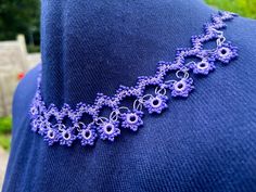 a purple necklace is displayed on a mannequin