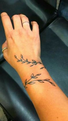 a woman's hand with a small tattoo on her left wrist and an olive branch in the middle