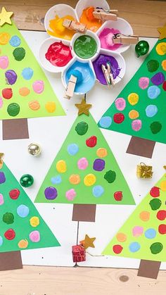 christmas trees made out of construction paper on a table with paint and crafting supplies