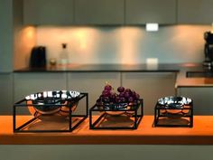 three metal bowls filled with fruit on top of a wooden counter