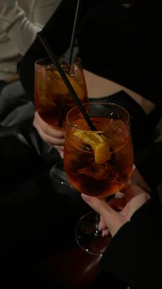 two people holding up glasses with drinks in them