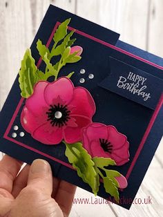 a hand holding up a card with flowers on it and the words happy birthday written in white