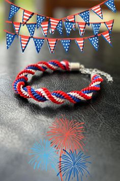 red, white and blue bracelets with fireworks on the side sitting on a table