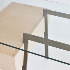 a glass table with a wooden box on top and metal frame around the edge, sitting on a white surface