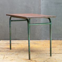 a small wooden table sitting on top of a hard wood floor next to a gray wall