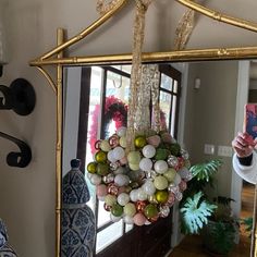 a woman taking a selfie in front of a mirror with ornaments hanging from it