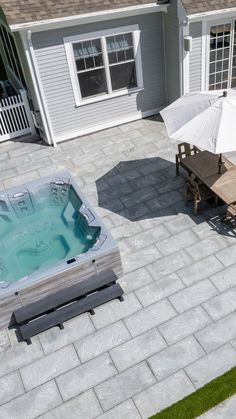 a hot tub sitting on top of a patio next to a table with an umbrella