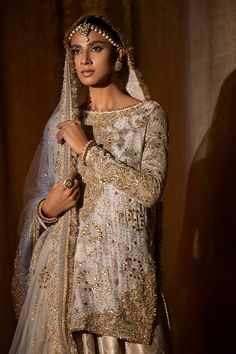 a woman in a white and gold bridal outfit