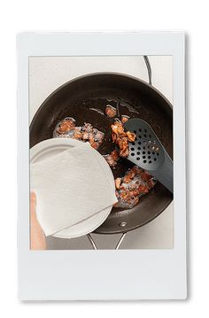 a person cooking food in a pan with a spatula