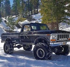 an old black truck is parked in the snow