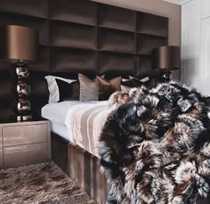 a bed with fur on it and two lamps next to it in a room that has brown walls